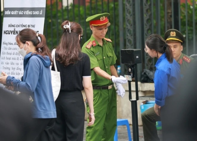 Lực lượng an ninh quét mã QR trên căn cước của người dân vào viếng Tổng Bí thư tại Nhà tang lễ Quốc gia. (Ảnh: TTXVN)