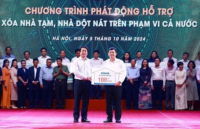  Đại diện Ngân hàng Thương mại Cổ phần Phát triển Thành phố Hồ Chí Minh (HDBank) trao tượng trưng kinh phí hỗ trợ xóa nhà tạm, nhà dột nát cho đại diện địa phương. (Ảnh: TTXVN)