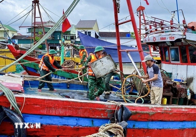   Cán bộ, chiến sỹ Đồn Biên phòng Diễn Thành (Bộ đội Biên phòng tỉnh Nghệ An) triển khai lực lượng hỗ trợ ngư dân đưa tàu thuyền vào nơi tránh trú bão, neo đậu, chằng néo phương tiện, thu dọn ngư lưới cụ. (Ảnh: TTXVN )
