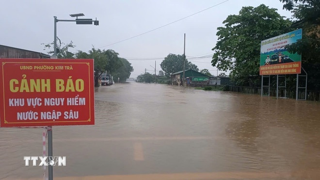   Chính quyền địa phương cắm biển cảnh báo nguy hiểm tại các vị trí xung yếu ngập sâu ở phường Kim Trà, thành phố Huế. (Ảnh: TTXVN)