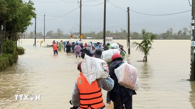 Người dân mang lương thực và nhu yếu phẩm về nhà sau nhiều ngày bị ngập. (Ảnh: TTXVN) Người dân mang lương thực và nhu yếu phẩm về nhà sau nhiều ngày bị ngập. (Ảnh: TTXVN)