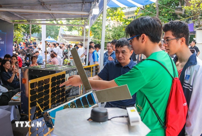   Học sinh tìm hiểu về các vệ tinh tại gian hàng trưng bày sản phẩm khoa học của Viện Hàn lâm Khoa học và Công nghệ Việt Nam. (Ảnh: TTXVN)