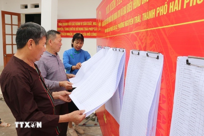 Người dân xem danh sách cử tri được niêm yết. (Ảnh: TTXVN)