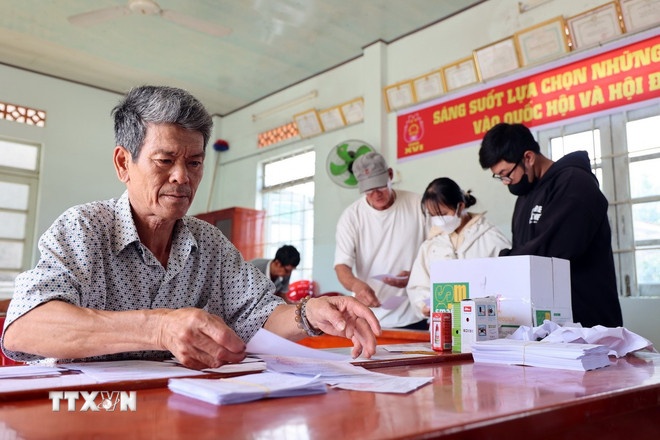 Các trưởng thôn kiểm tra thẻ cử tri, trang trí hội trường thôn. (Ảnh: TTXVN)