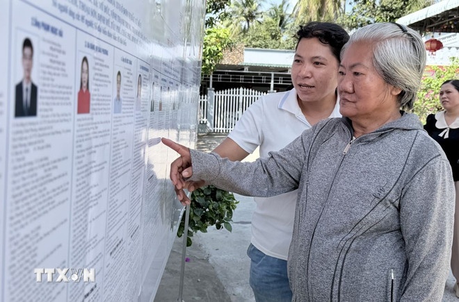 Cử tri xã Tri Tôn, An Giang xem danh sách cử tri được niêm yết công khai tại khu vực bỏ phiếu. (Ảnh: TTXVN)