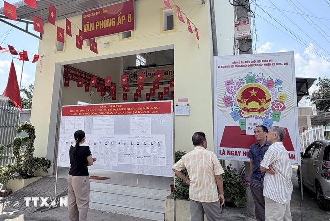 Cử tri theo dõi bảng niêm yết danh sách ứng cử viên và pa nô cổ động ngày bầu cử tại Văn phòng ấp 6, xã Tri Tôn, An Giang. (Ảnh: TTXVN)